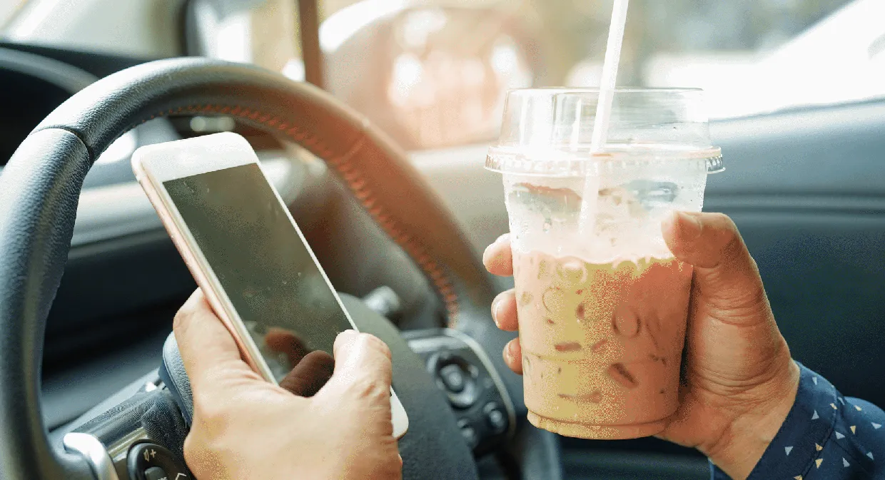 man texting and drinking coffee while driving